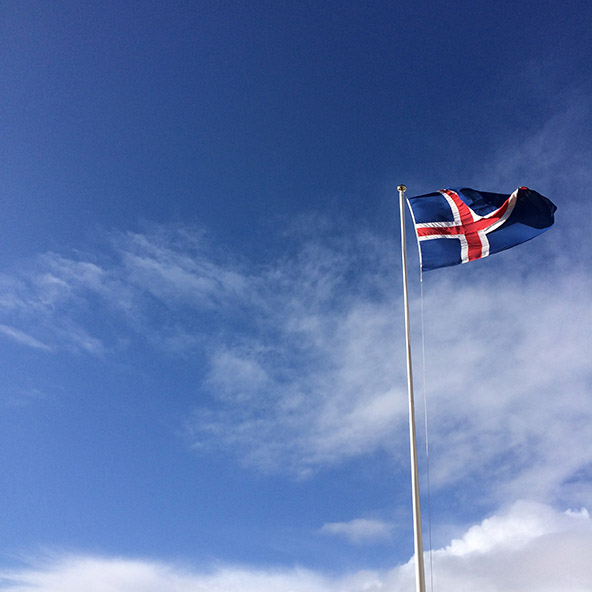The flag of Iceland fluttering in a blue sky near Budir, Iceland | meljoulwan.com